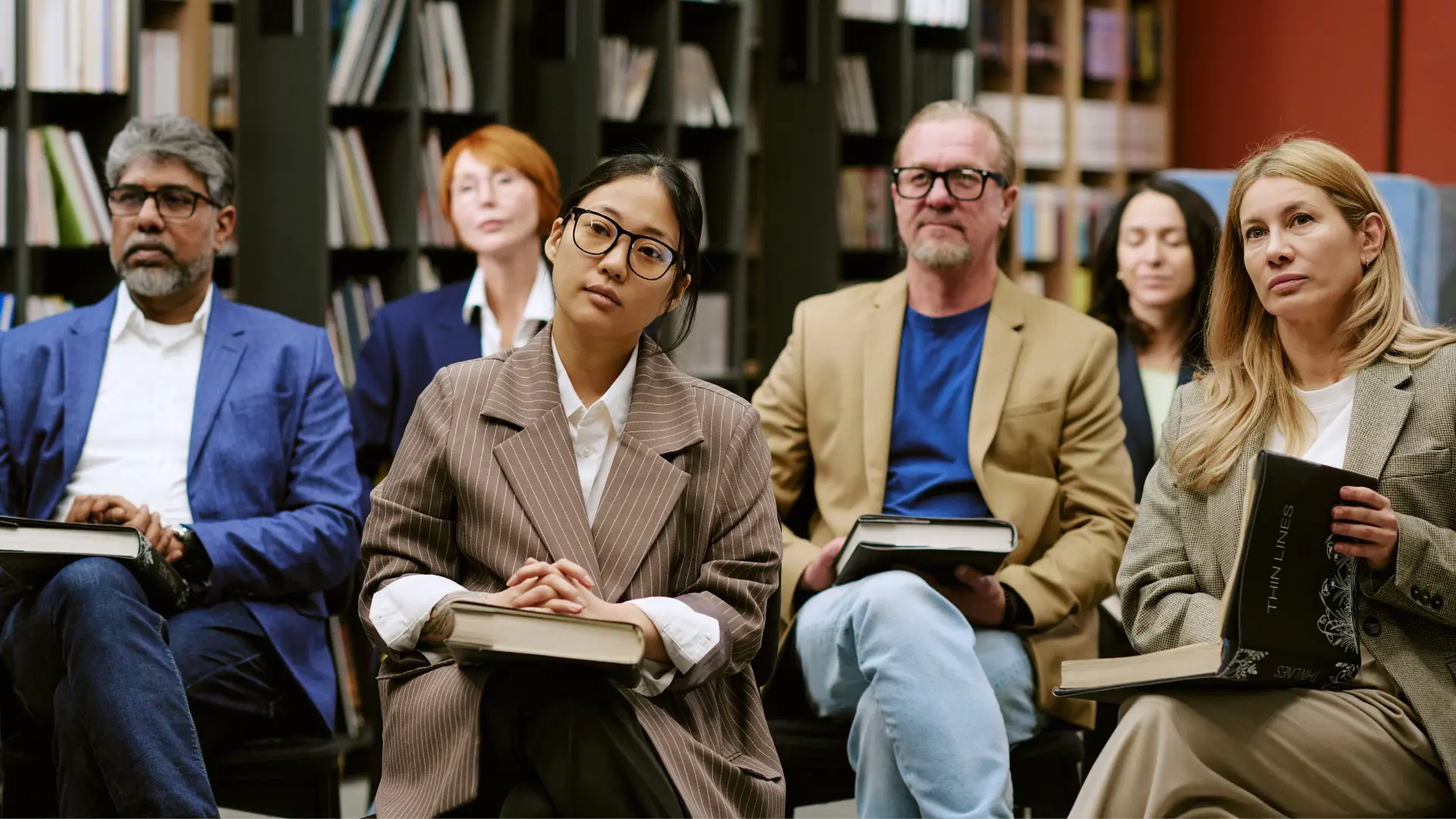 A panel of scholars seated with books at an academic session
