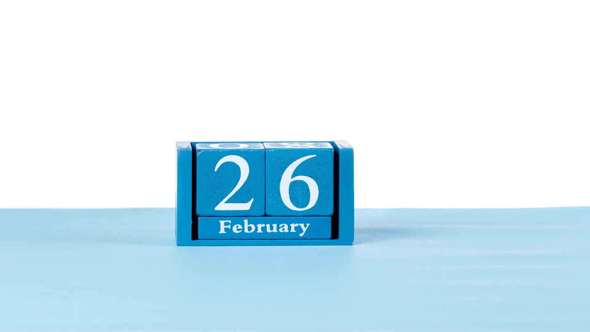 A wooden block calendar showing 26 February, the conference start date